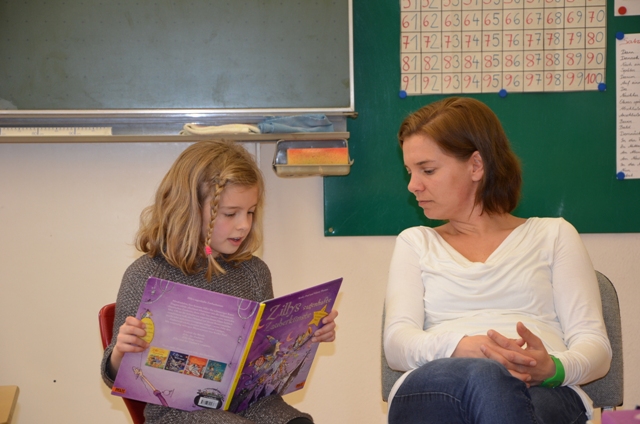 Eine Mutti hilft der Schülerin aus der 2a Klasse bei der Buchvorstellung